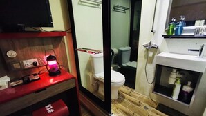 A compact bathroom with a toilet, sink, and a small table with a red lamp. - KMB hostel (Kowloon)