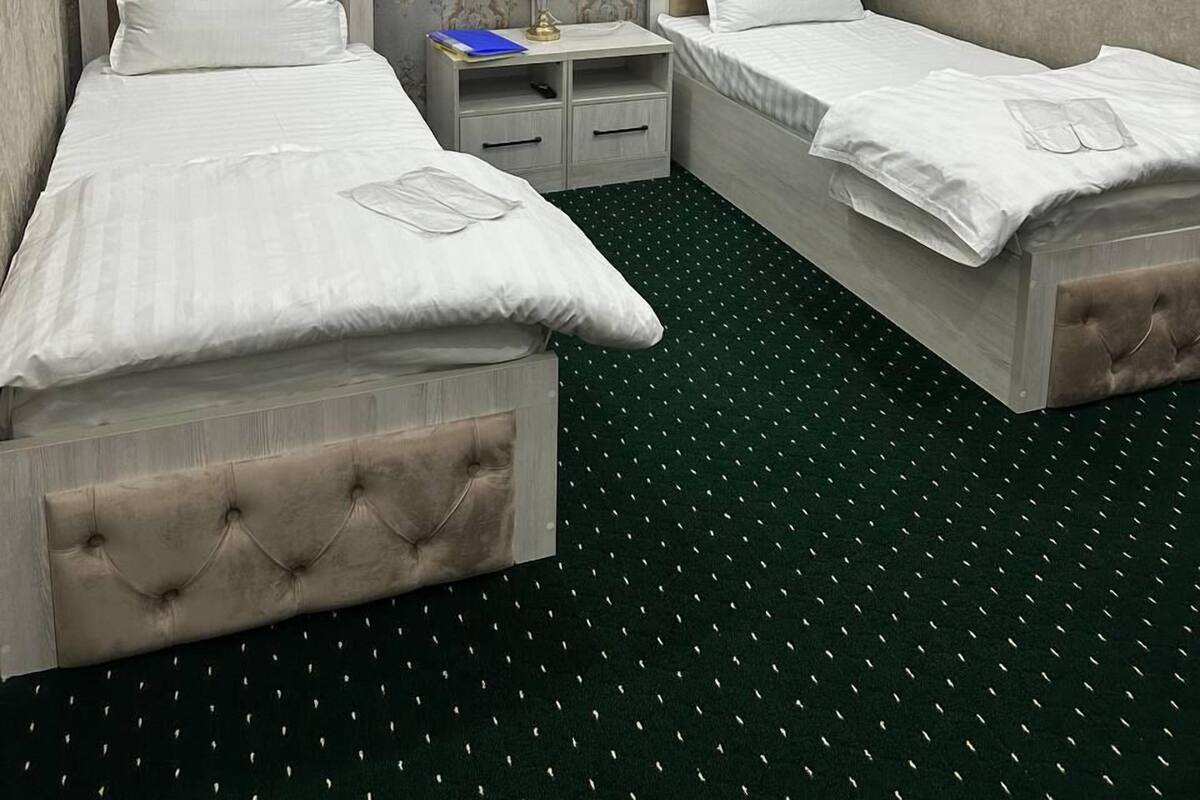 Habitación de hotel con dos camas, una mesita de noche, una lámpara y un aire acondicionado.