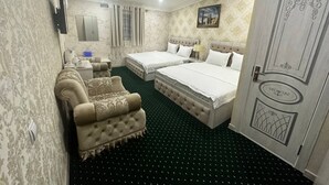 A hotel room with two beds, a sofa, a desk, and a television. - Semurg Hotel (Tashkent)