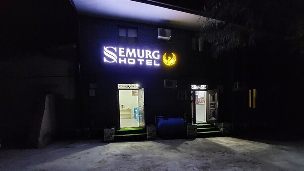 The exterior of Semurg Hotel with two illuminated entrances and a concrete ground. - Semurg Hotel (Tashkent)