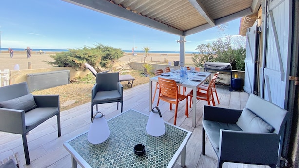 An outdoor patio with a table and chairs, a covered seating area, and a view of the beach. - Seafront house (Fleury)