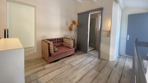A room with a wooden floor, a sofa, a door, and a lamp. - Seafront house (Fleury)
