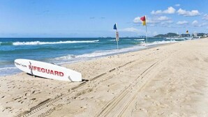 Un poste de surveillance des sauveteurs se dresse sur une plage de sable, avec les vagues de l’océan en arrière-plan.