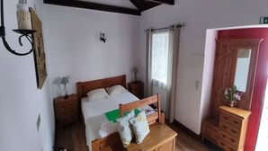 A bedroom with a wooden bed, a nightstand with a lamp, a dresser, and a mirror. - Oxen Car House 1 Bedroom (Capelo)