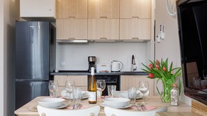 Una cucina moderna con un frigorifero nero, mobili in legno e un tavolo da pranzo per quattro, apparecchiato con bicchieri da vino e una bottiglia.