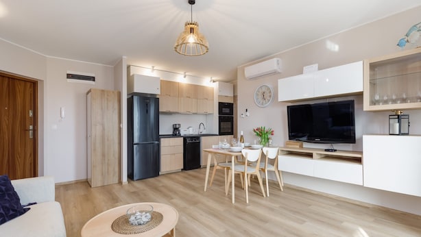 Una cucina moderna con mobili in legno, un'area pranzo con tavolo e sedie, un televisore e una lampada a sospensione.