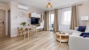 Un soggiorno moderno con zona pranzo, TV a schermo piatto e divano.
