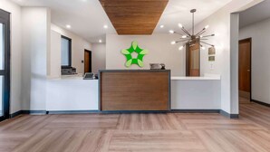 A modern reception area with a wooden ceiling, a green logo on the wall, and a reception desk.