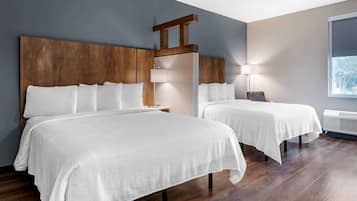 A hotel room with two beds, wooden headboards, a large window, and a wall-mounted air conditioner.