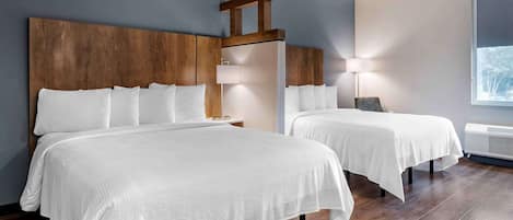 A hotel room with two beds, wooden headboards, a large window, and a wall-mounted air conditioner.