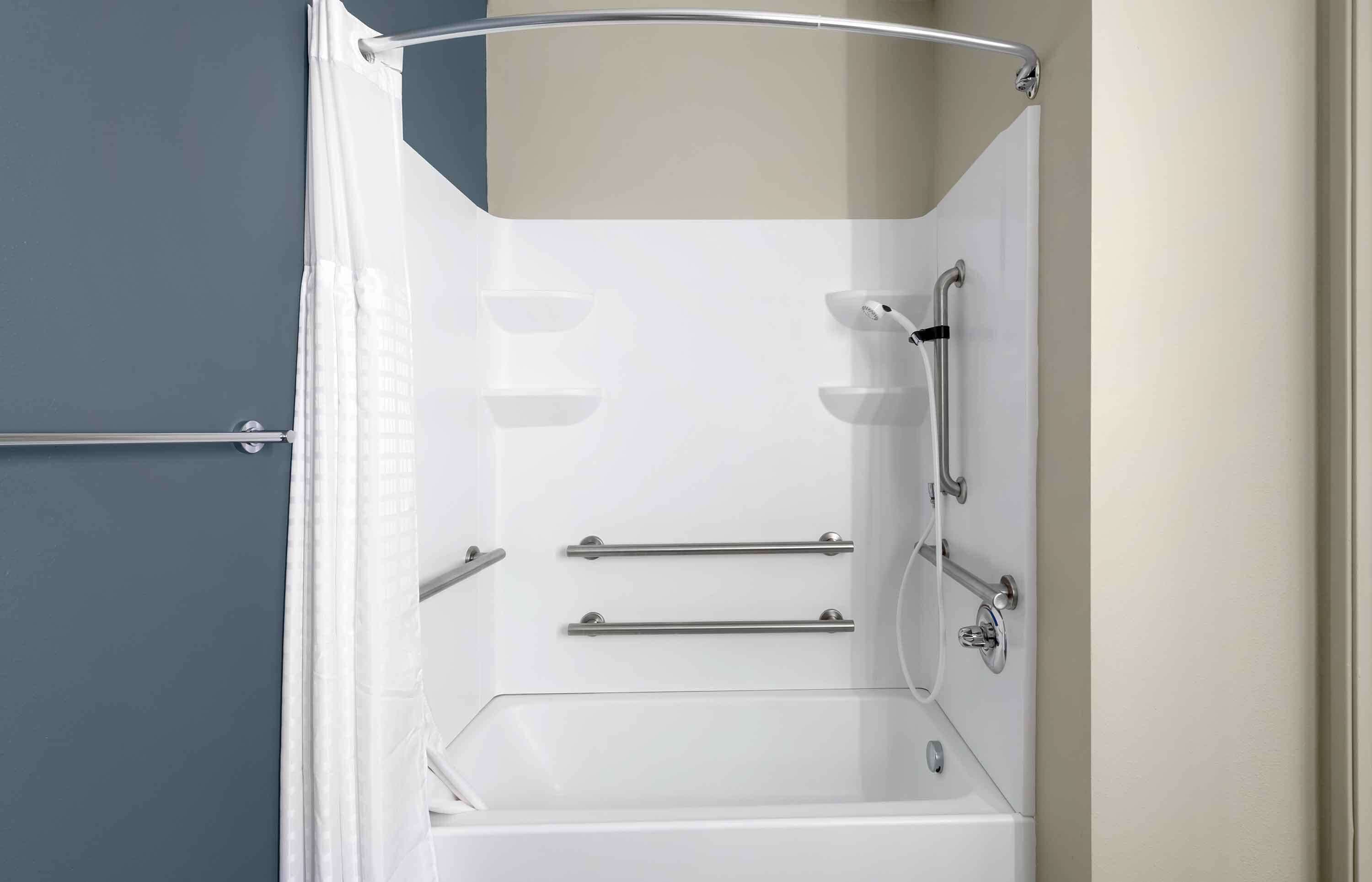A modern bathroom with a walk-in shower, grab bars, and a bathtub.
