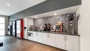 A modern kitchen with white cabinets, a black backsplash, and a coffee machine.