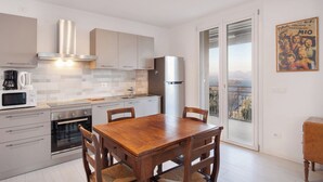 A modern kitchen with a dining area, a refrigerator, and a view of a cityscape through the window. - Villa Malù - APT Amalia - Pool and lake view (Torri del Benaco VR, Italia)