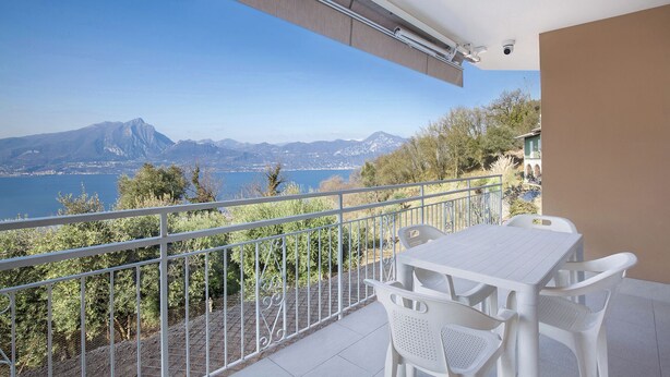 A balcony with a table and chairs, overlooking a scenic view of mountains and a lake. - Villa Malù - APT Amalia - Pool and lake view (Torri del Benaco VR, Italia)