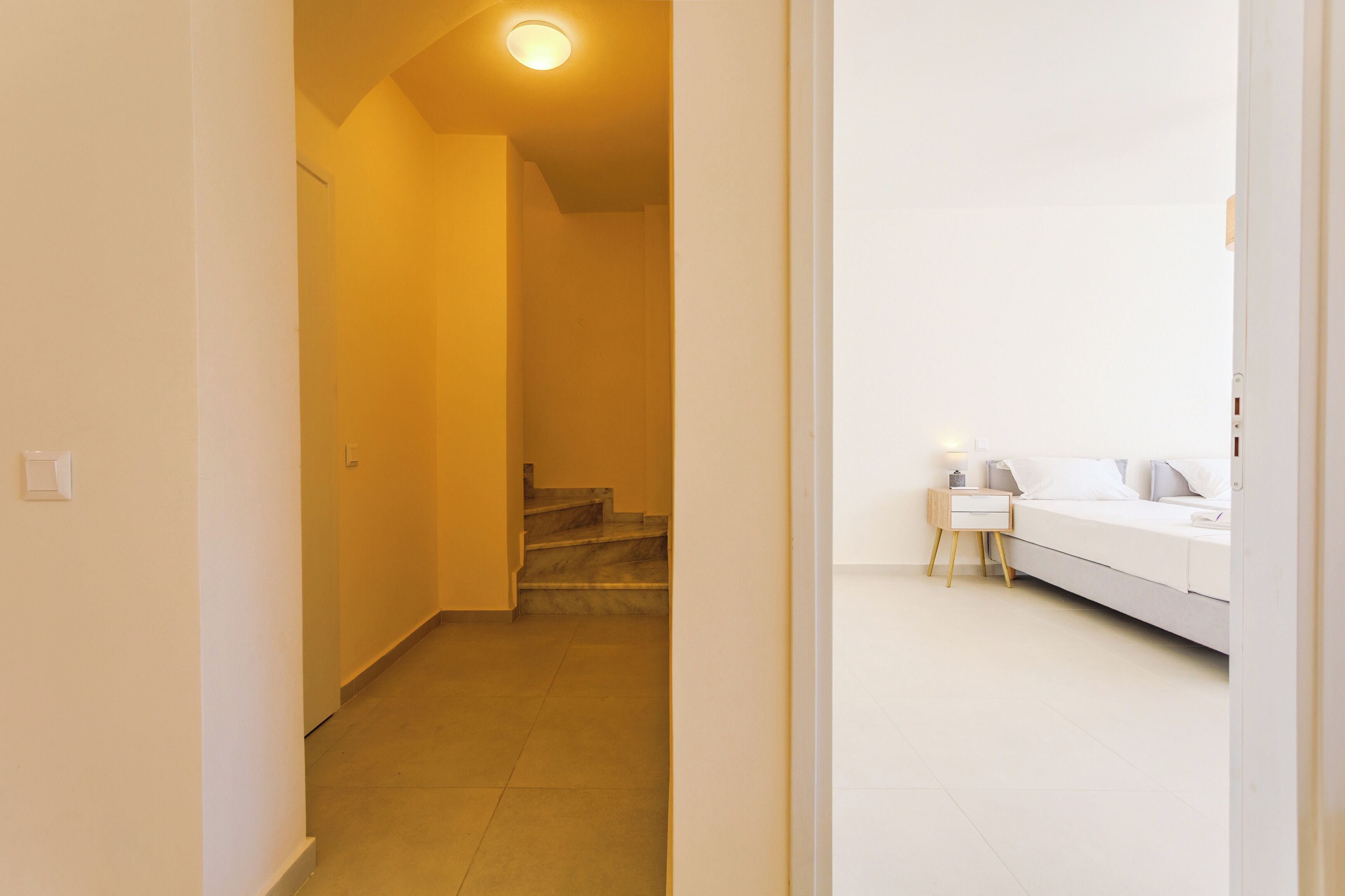 Quarto com cama, mesa de cabeceira e apoio para objetos pessoais.