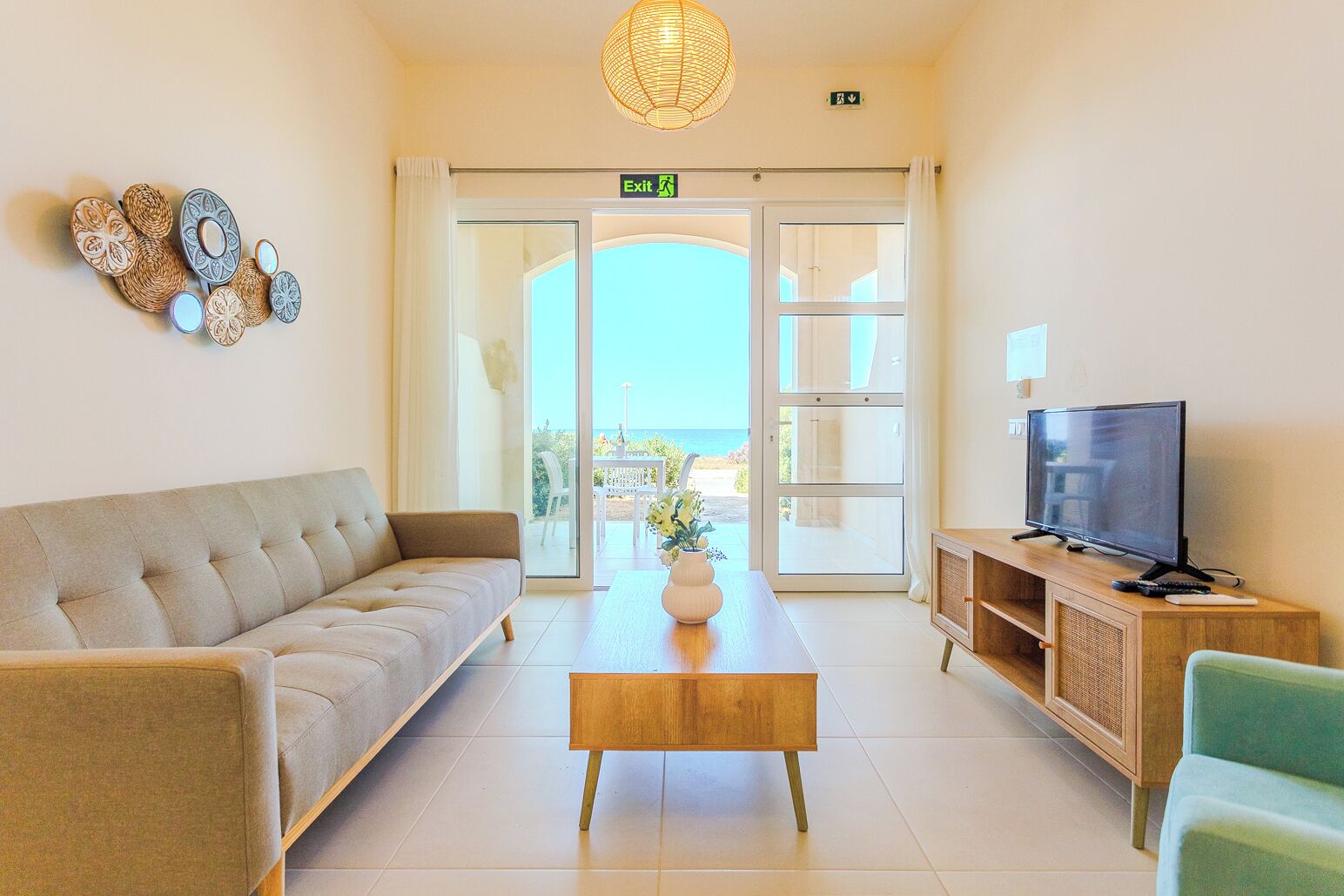 Ein Wohnzimmer mit Sofa, Couchtisch, Fernseher und Blick ins Freie.