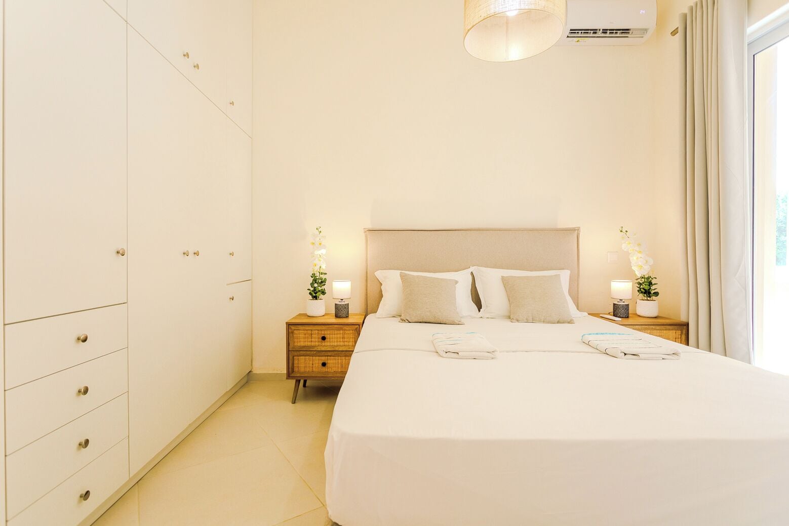 Una habitación de hotel con una cama grande, dos mesitas de noche, un armario y un aire acondicionado.
