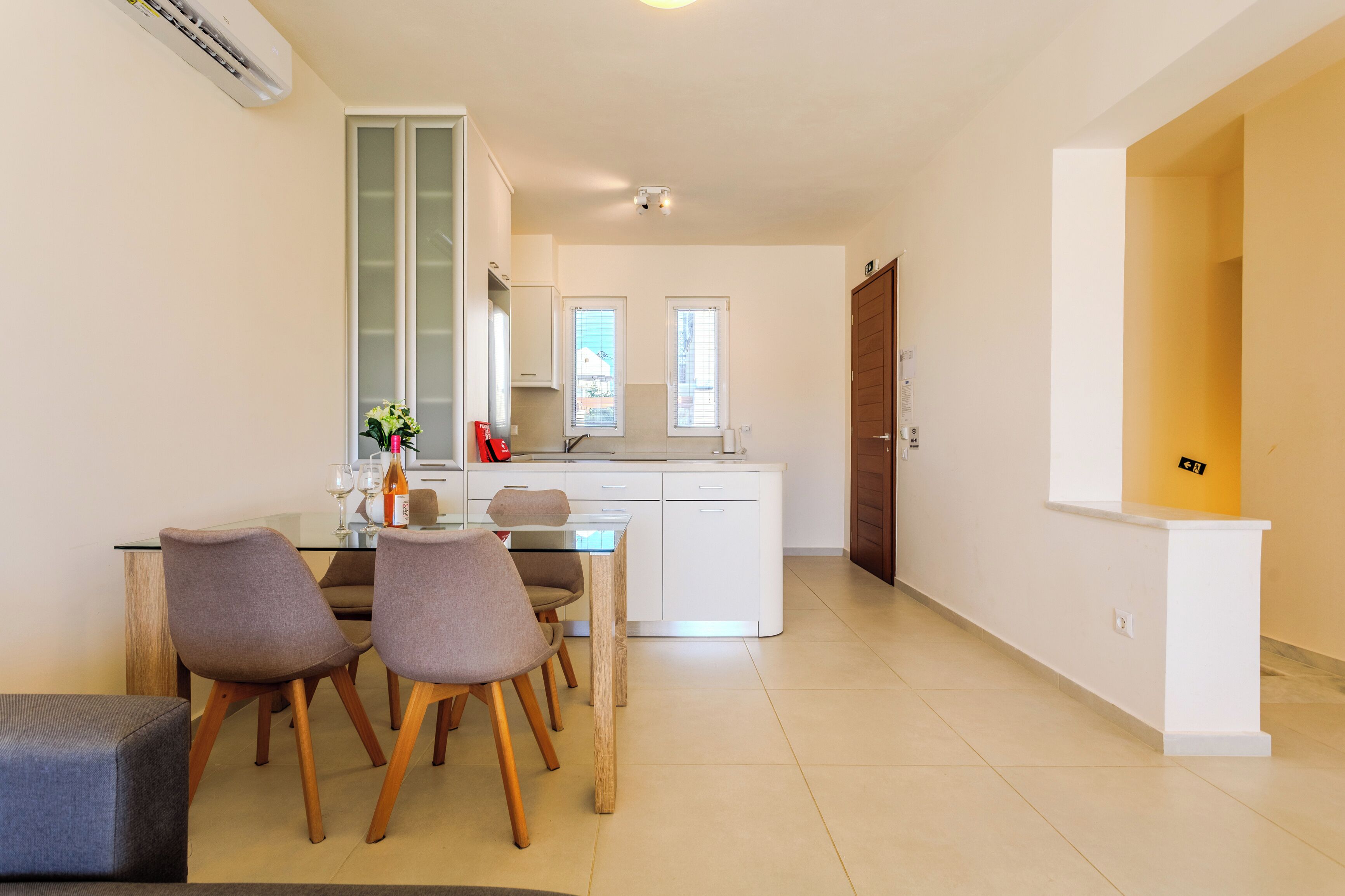 Una cocina moderna con armarios blancos, una mesa de comedor con sillas y una pequeña isla.