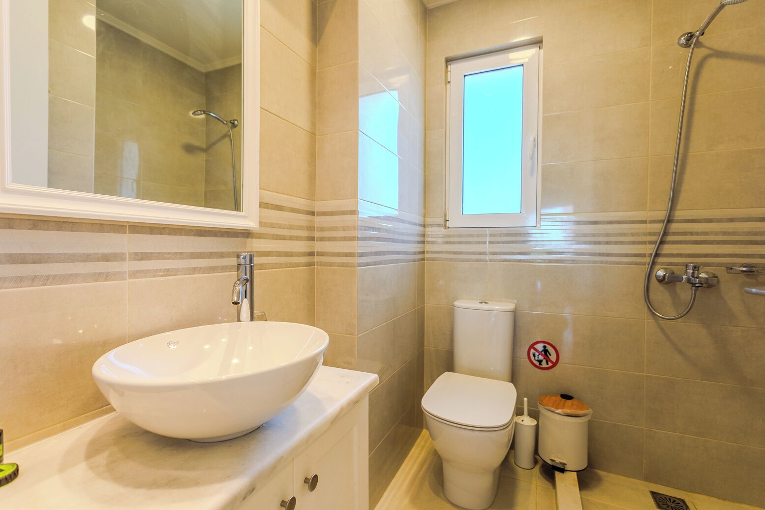Une salle de bain avec un grand lavabo blanc, des toilettes et une douche.