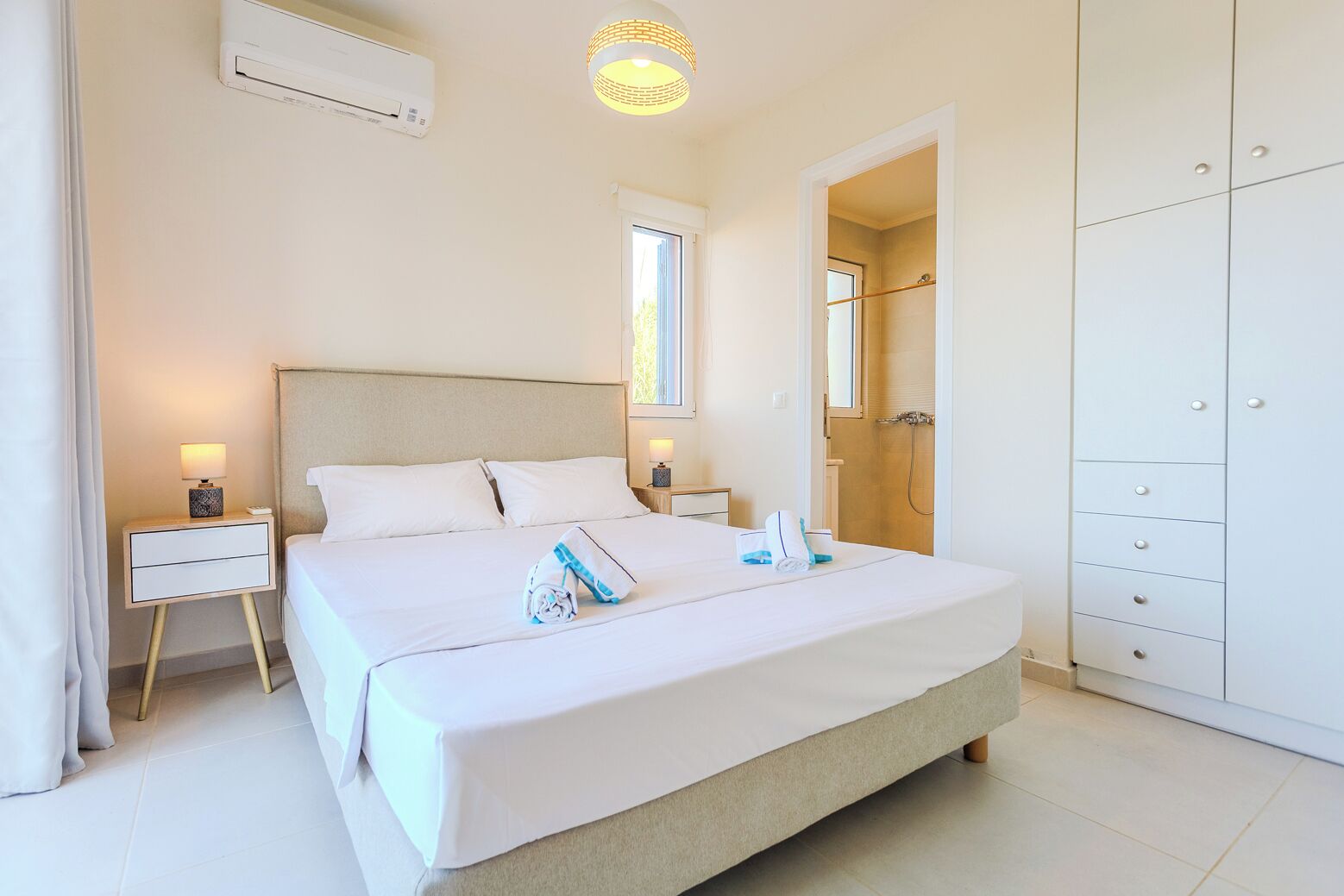 A hotel room with a bed, bedside table, lamp, and a wardrobe.