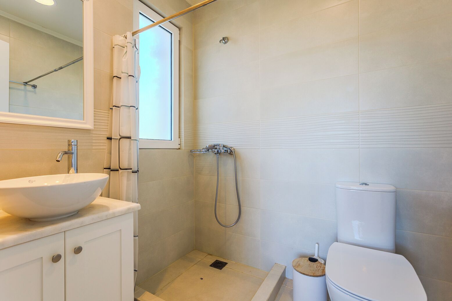 Un bagno con un lavandino bianco, un WC e uno spazio doccia.