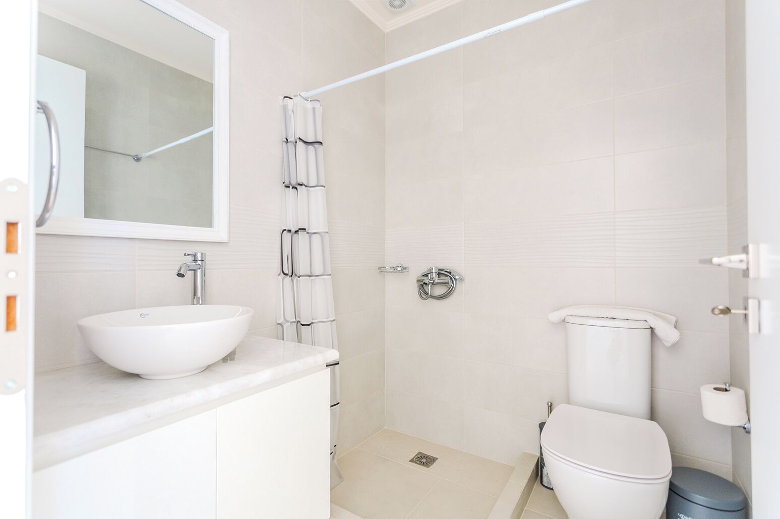 A bathroom with a white sink, mirror, toilet, and shower.