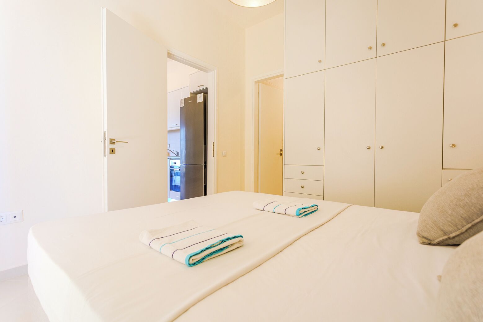 A bedroom with a bed, a wardrobe, and a door leading to a kitchen.