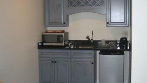 Una cocina compacta con armarios grises, un microondas, una cafetera y un lavavajillas.