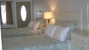 Un dormitorio con dos camas, una ventana con cortinas, una lámpara y un aparador.