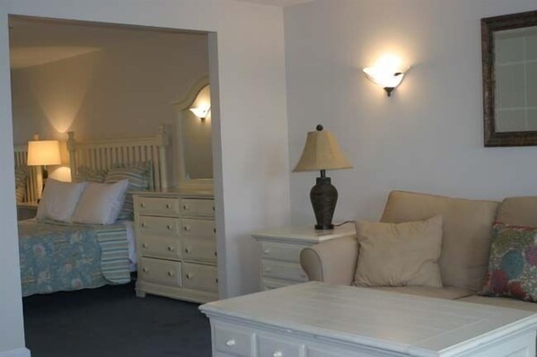 Une chambre à coucher comprenant un lit, une commode, une table de chevet avec une lampe et un canapé.