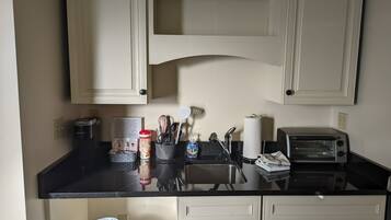 A kitchen with white cabinets, a black countertop, a toaster, and various kitchen utensils.
