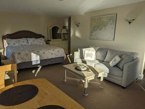 A bedroom with a bed, a dresser, a nightstand, a lamp, a map on the wall, and a sofa.