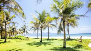 A tropical landscape with palm trees and a beach. - Luxury Pool Villas in Purama Villas (Da Nang)