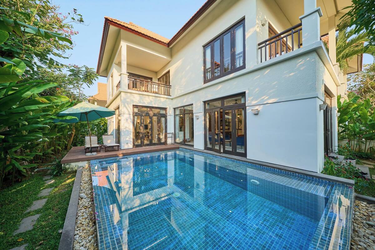 A modern two-story house with a swimming pool, large windows, and a balcony.
