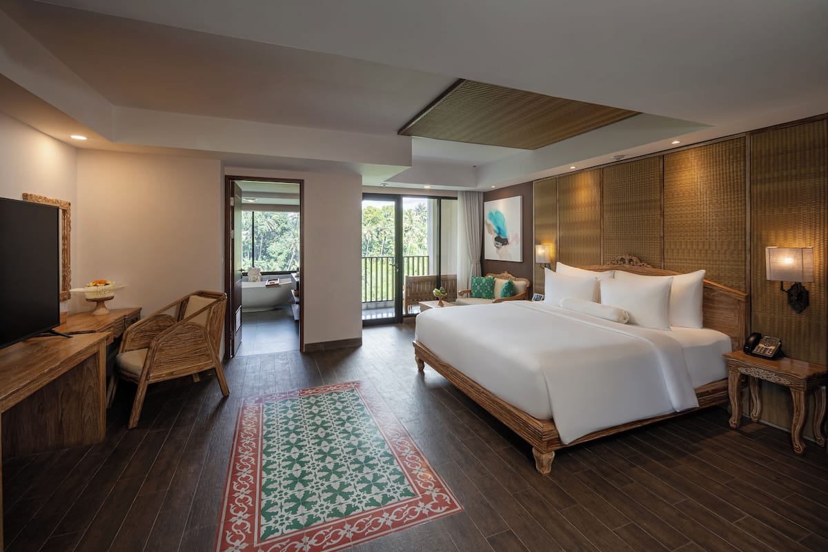 A spacious bedroom with a large bed, wooden furniture, and a view of the outdoors.