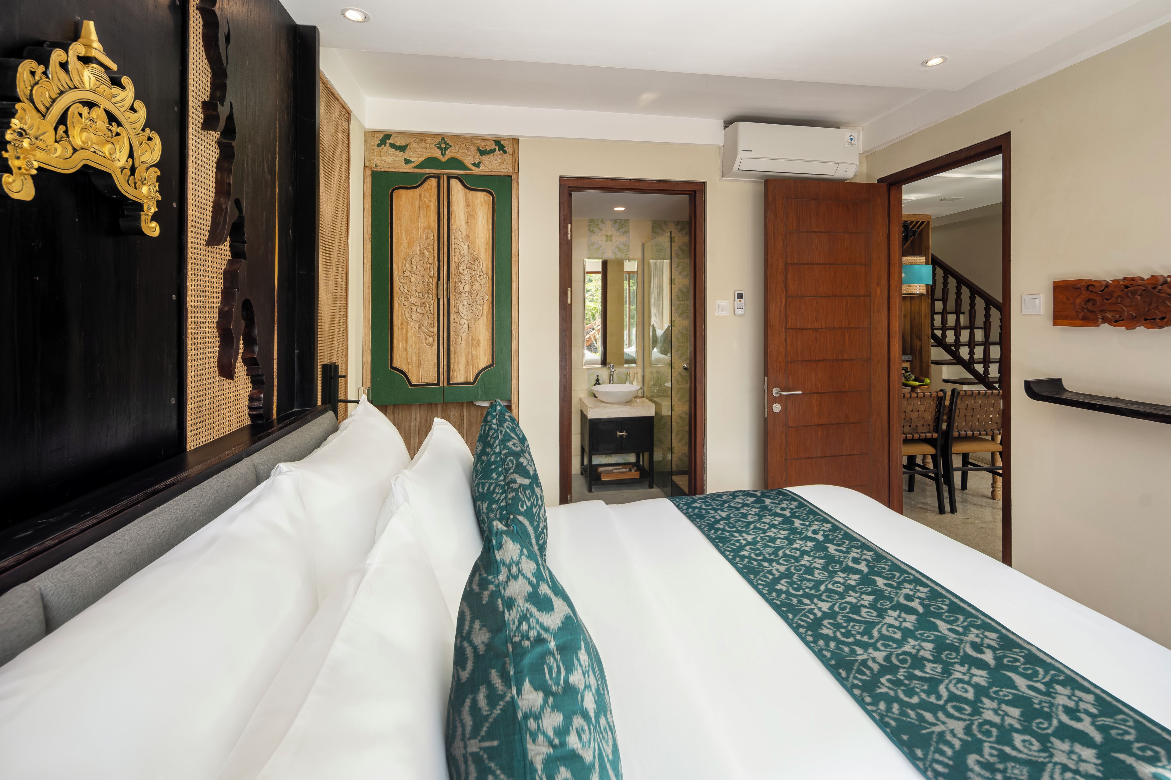 A hotel room with a bed, a bathroom, and a staircase.
