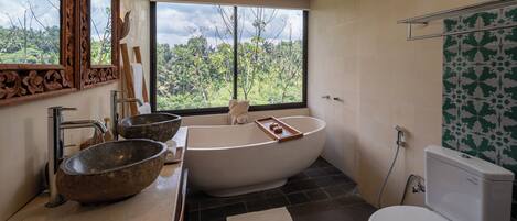 Une salle de bain moderne avec une baignoire sur pieds, un grand miroir et une vue sur l’extérieur.