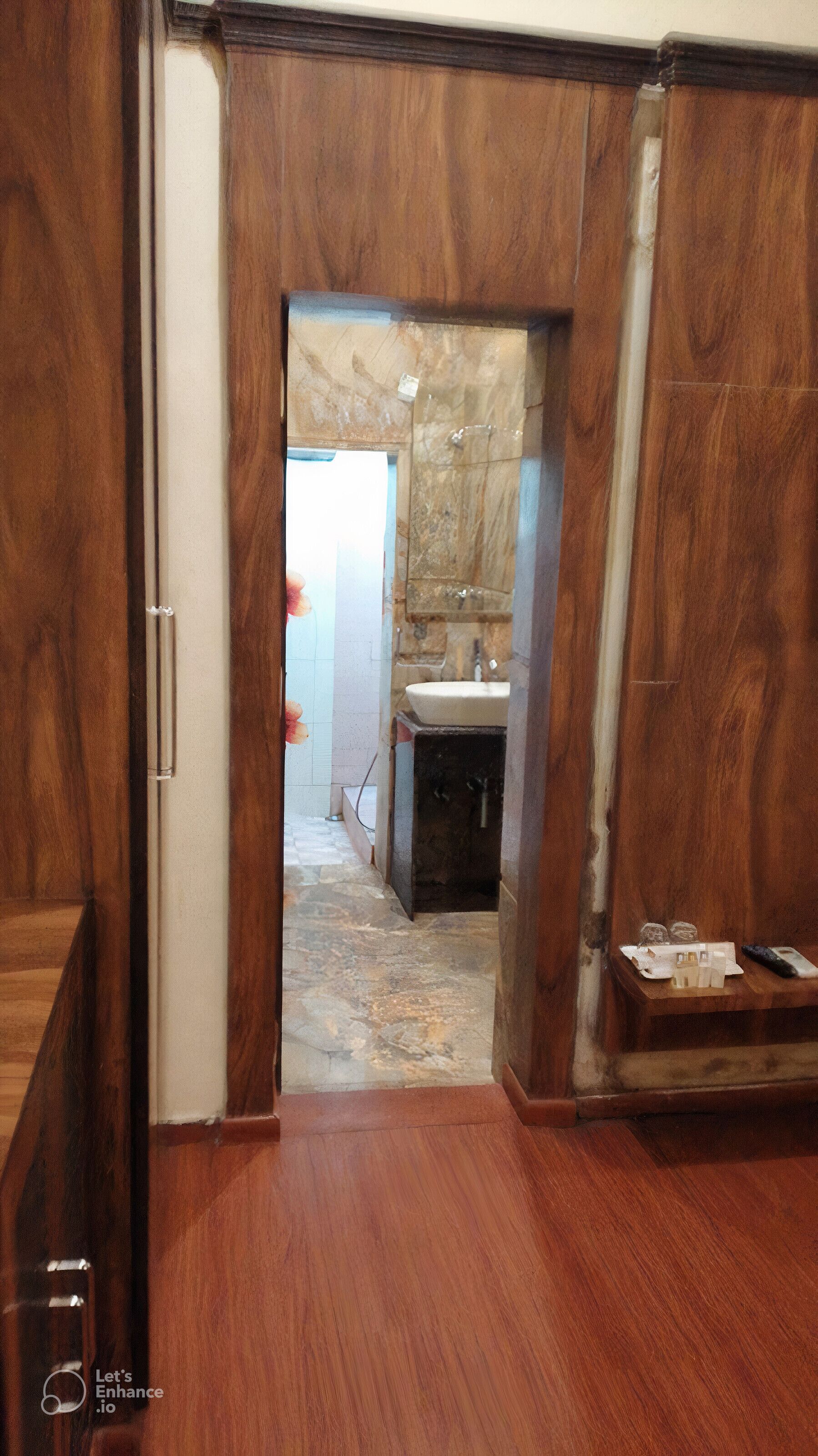 A wooden hallway leading to a bathroom with a sink and a mirror.