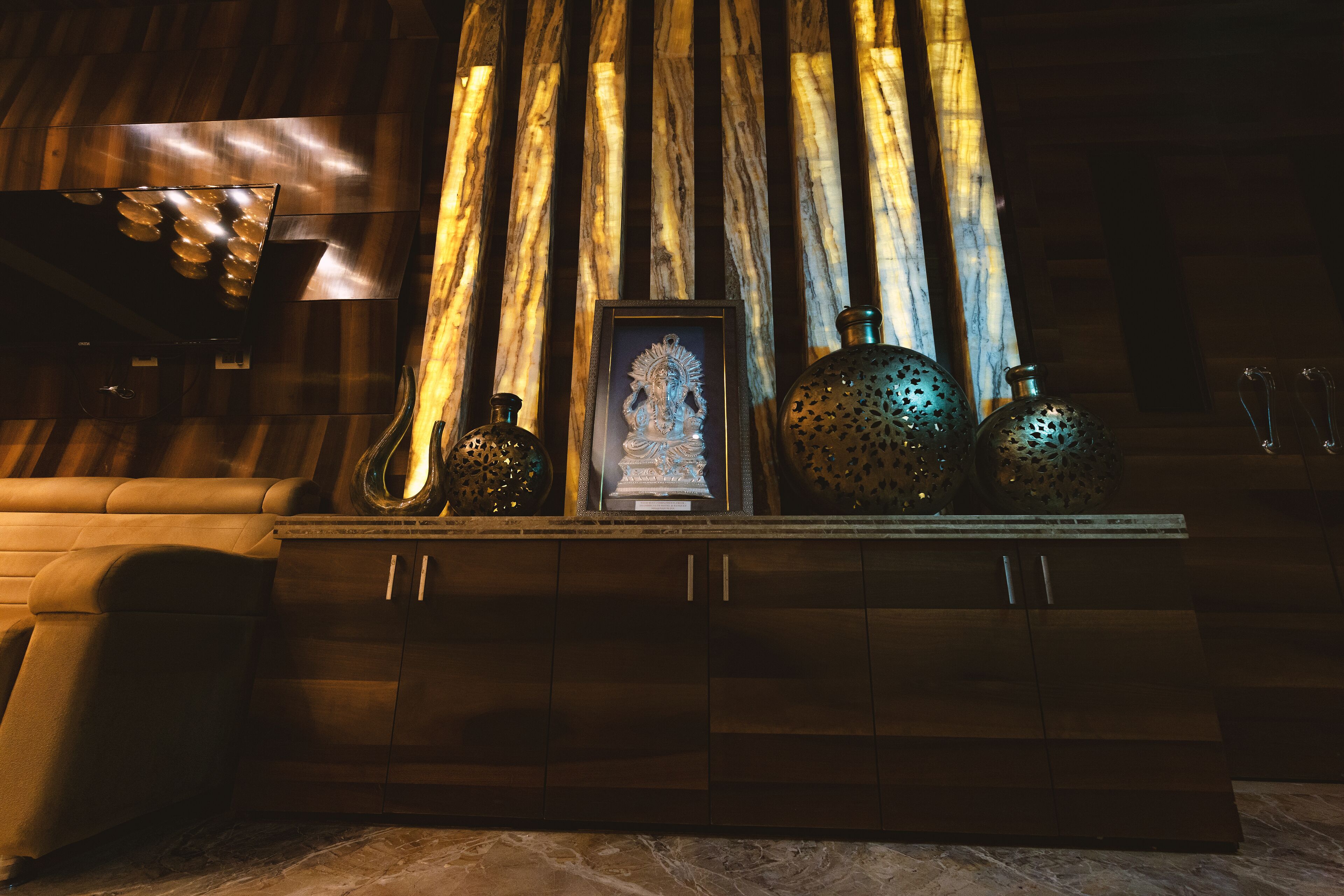 A wooden cabinet with a framed statue, decorative vases, and a small table with a lamp.