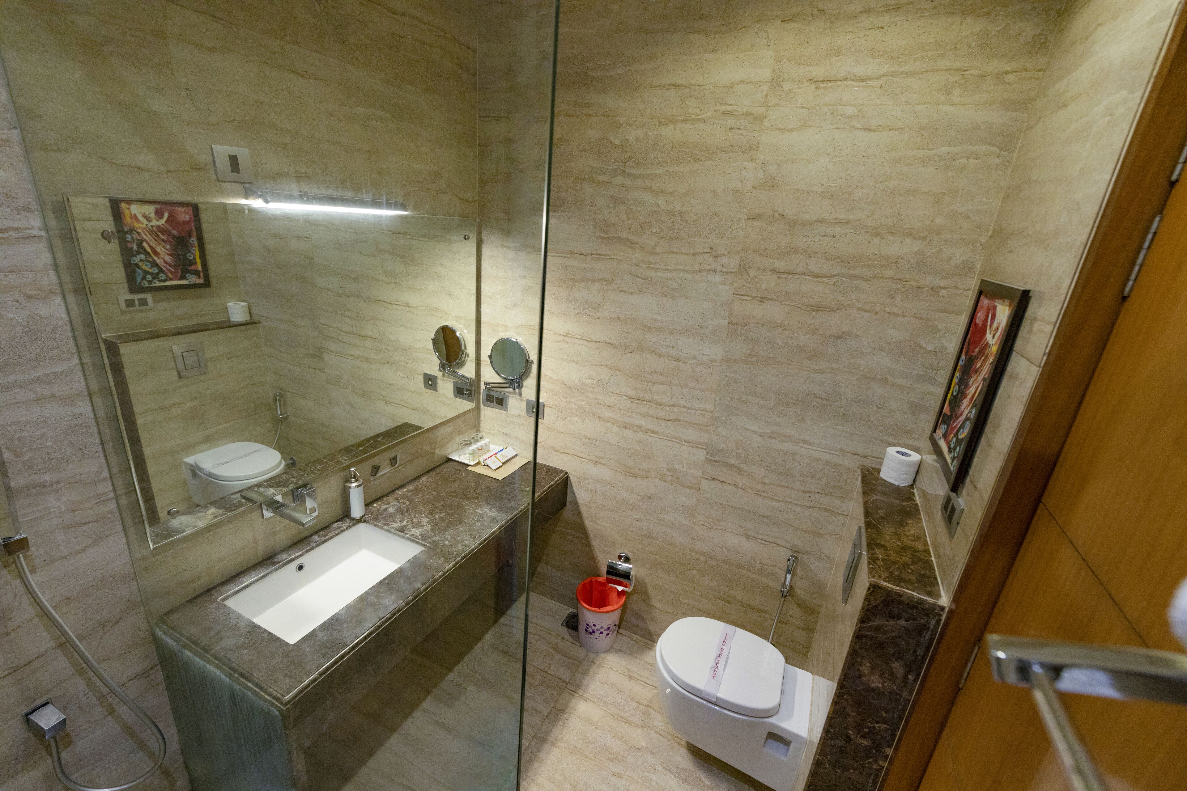 A modern bathroom with a glass-enclosed shower, a sink, and a toilet.