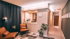 A modern hotel lobby with a reception desk, seating area, and a large potted plant. - R Hotel-The Atelier Shinsaibashi East (Osaka)