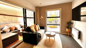 Un salon moderne avec un canapé, une table basse et une grande fenêtre donnant sur la ville.