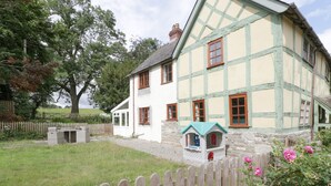 A traditional half-timbered house with a small playhouse, a wooden fence, and a grassy yard. - The Old Rectory (Presteigne)