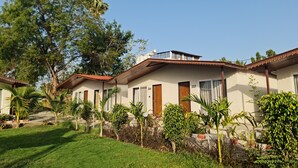 Una hilera de edificios de una planta con puertas numeradas, rodeada de céspedes y árboles cuidados.