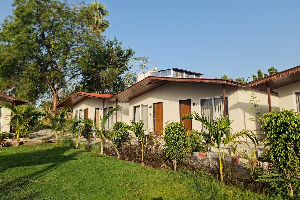 A row of single-story buildings with numbered doors, surrounded by well-maintained lawns and trees.
