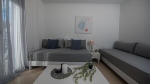 A modern bedroom with a bed, a sofa, a bedside table, and a wall art piece.