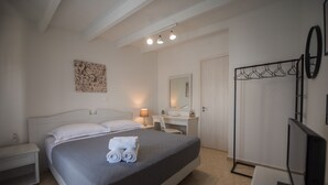 A bedroom with a bed, bedside table, desk, mirror, and wardrobe.