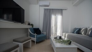 A modern living room with a blue armchair, a grey sofa, a white coffee table, and a white bench.