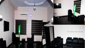 A hotel lobby with black leather seating, a reception desk, and a large window with blinds. - j14 hotel and suites (Lagos)