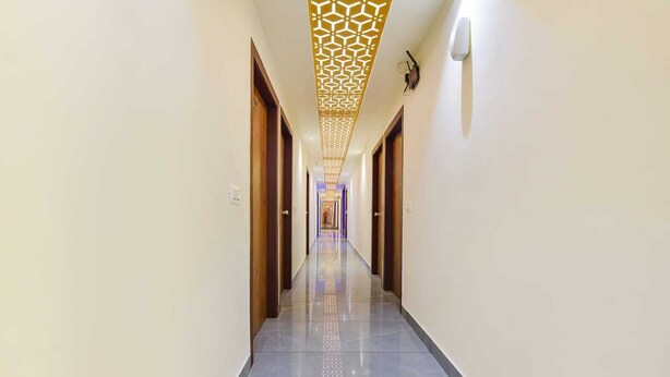 A long, narrow hallway with a patterned ceiling and a reflective floor. - Hotel Avadh Palace (Ahmedabad)